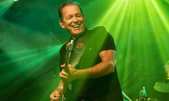Tommy Castro wears black clothing and performs live on stage.