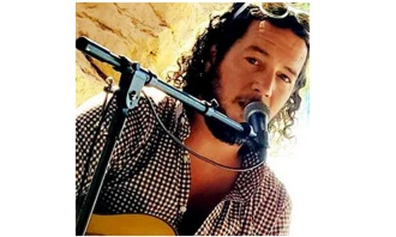 Musician John Fowler at the microphone, onstage. 