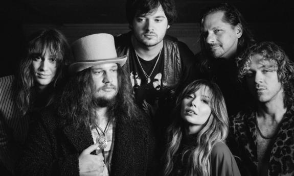 Bandmates from Parker Barrow huddle together and pose in front of a black backdrop.