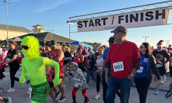 Runners and walkers wearing holiday costumes or exercise gear in the Santa Suits on the Loose in 2025 