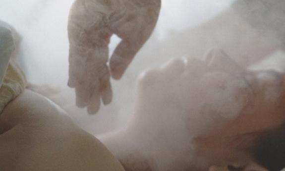 A client bathed in steam during a treatement from an esthetician