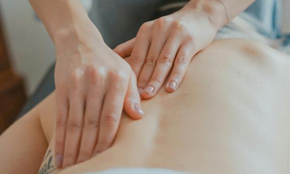 The hands of a woman gently massaging a client's back
