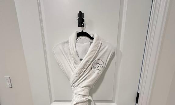 A white robe folded and hung on a door, ready for a spa guest