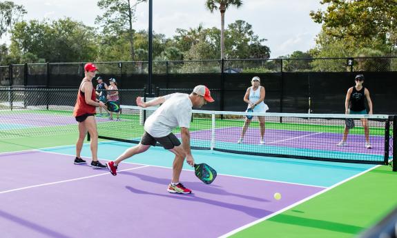 Four people playing paddleball on brightly-colored courts at the Yards