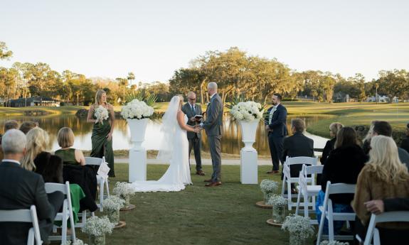 A couple getting married outside near a pond at The Yards