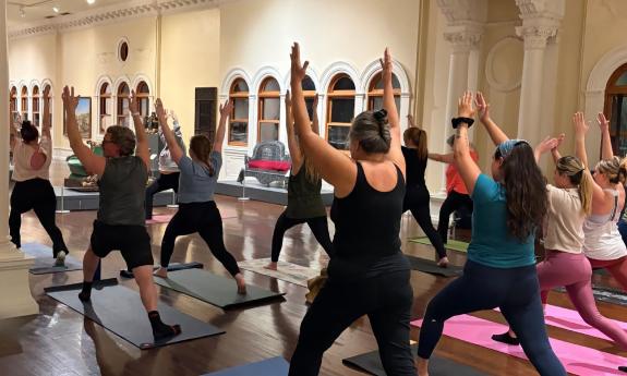 A yoga class in the atrium around the ballroom at the Lightner Museum