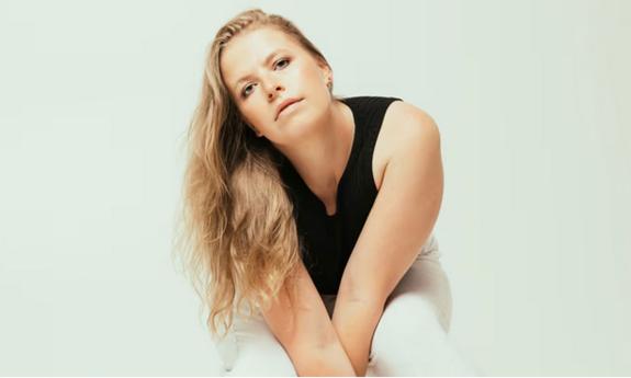 Songwriter Charlotte Morris promo shot, in black tank top and white slacks