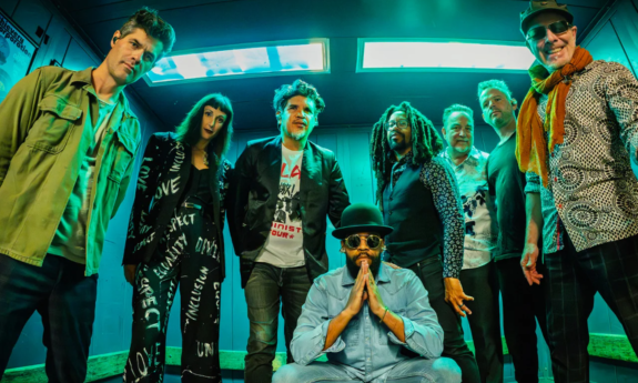 Bandmates from Thievery Corporation pose in front of a wall.