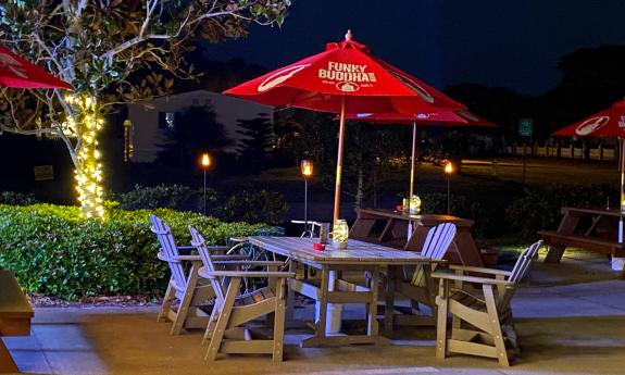 An outdoor dining table with a lighted umbrella at Back 40 A1A