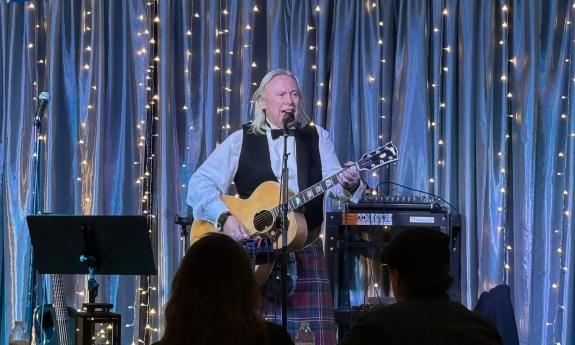 Bill Mullen on stage with his guitar, in front of a live audience