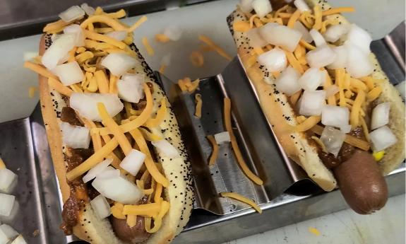 A Chili dog with cheese and onions added on top