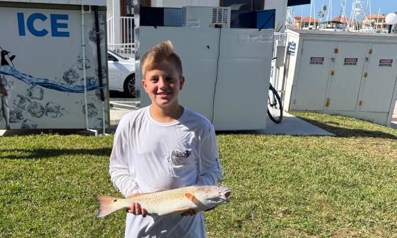 A young man holding a winning fish at a local fishing tournament