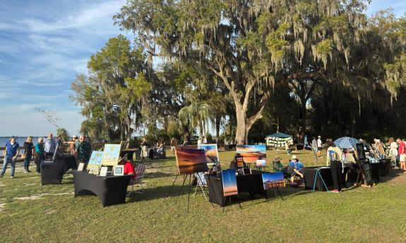 Artists show their works around the tall trees at Alpine Groves Park