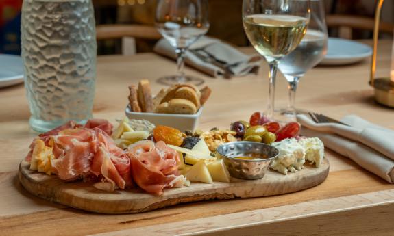 A charcuterie board and a glass of wine