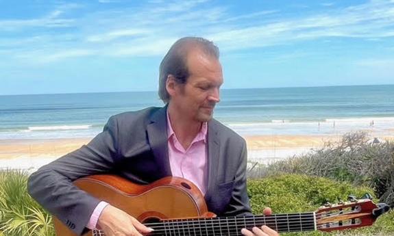 Guitarist Jonathan Lee Dotson playing on a seawall overlooking the Atlantic Ocean