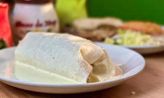 A burrito with queso on top