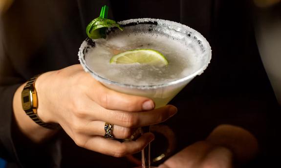 A person holding a chilled margarita glass 