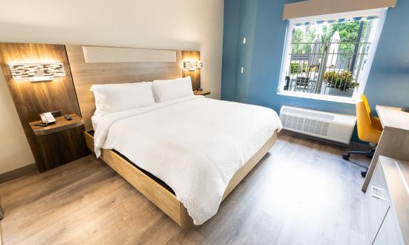 A hotel room with a king bed, teal accent wall, and desk