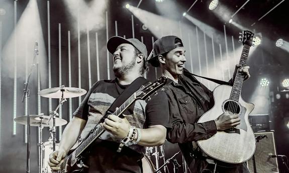 Johnny Cosmic and KBong performing on stage with guitars