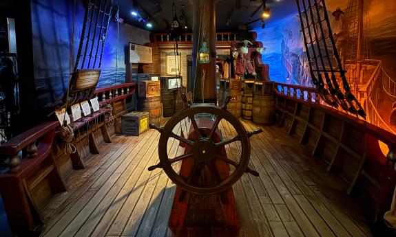 The deck of a pirate ship, with ship's wheel and lines for the sails