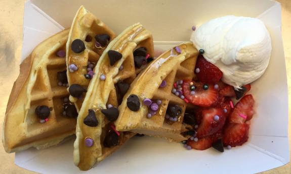 Waffles topped with chocolate chips, sprinkles, fruit, and cream