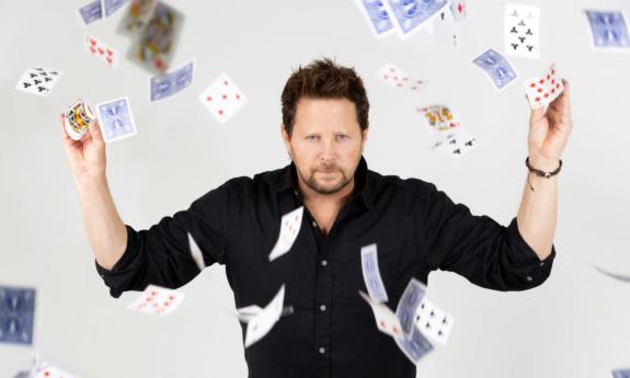 Andy Gross poses with cards that float from his hands.