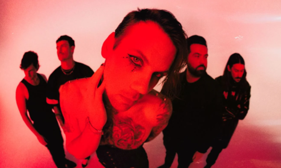 Bandmates from Beartooth wear dark clothing and pose in front of a red backdrop.