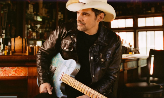 Brad Paisley poses with a white cowboy hat and matching guitar.