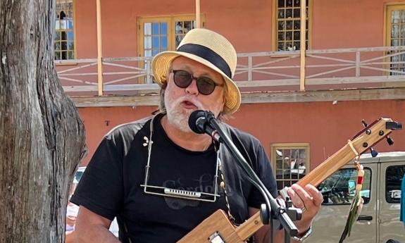 musician, singer-songwriter Devid Reed playing a cigar box guitar, outdoors