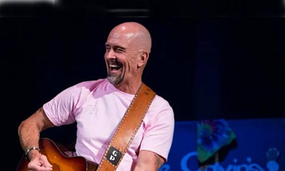 Grant Peeples onstage with his guitar and smiling