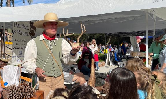 A man portraying William Bartram holding a deer skull while talking with children