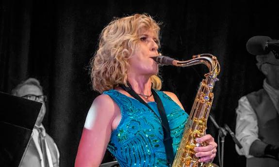 Shari Little playing her saxophone on stage with Teal Cabana Band