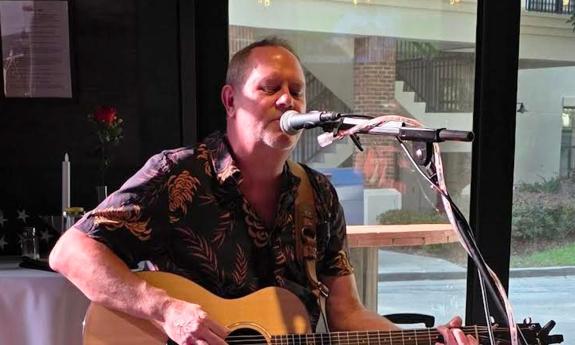 Musician Simply Shane behind the mic, with his guitar, singing