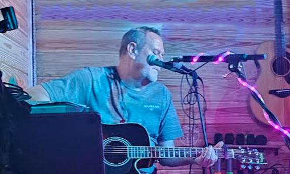 musician Simply Shane onstage at microphone, with guitar