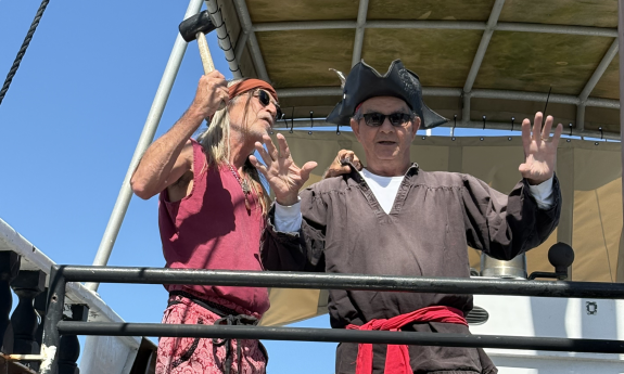 One pirate "arrests" the another while holding a mallet