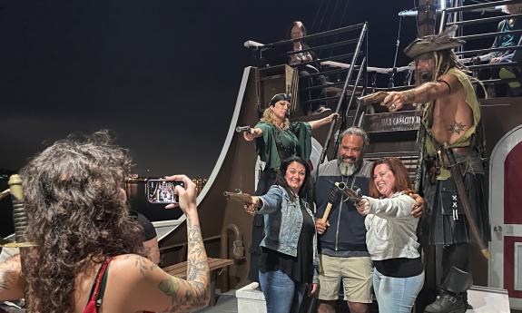 Guests aboard the Rum Runners Cruise pose with pirates