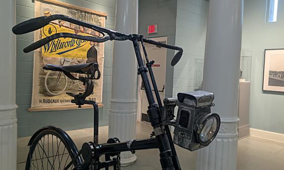 The front of an antique bicycle with a gas headlight