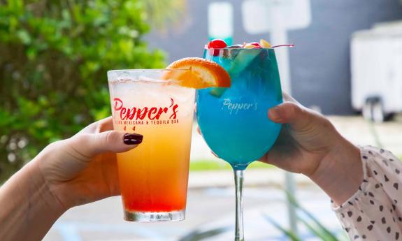 Two guests raising their cocktails in a toast at Pepper's 