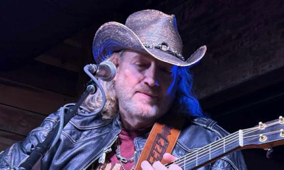 Songwriter Anthony Smith with his guitar, perfroming in cowboy hat