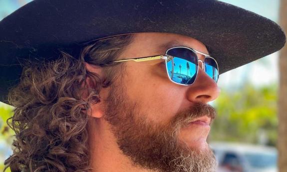 Side view of musician Banjo Brown in sunglasses and black hat