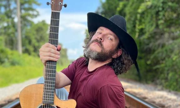 Banjo Brown with guitar, on a railroad track