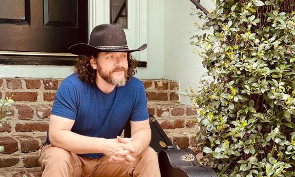 Banjo Brown sitting on brick steps, in black cowboy hat
