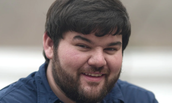 Ethan Philips dons a dark blue shirt and smiles for fans.