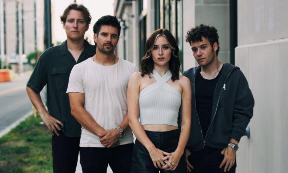 Members of First To Eleven, dressed in black and white, strike a pose on a city street.