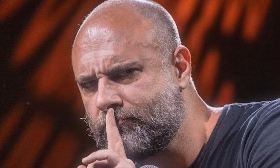 Kurt Metzger poses with an index finger on his lips.