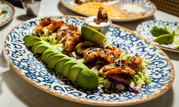 A plate of shrimp served with slices of avocado