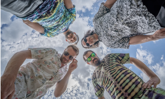 The members of Spafford, dressed in colorful shirts, pose while looking down toward the camera, creating a fun and distinctive perspective.