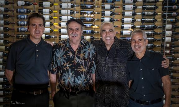 House Cats band in front of a wall of sine bottles. Photo courtesy of Terry Bottom photography