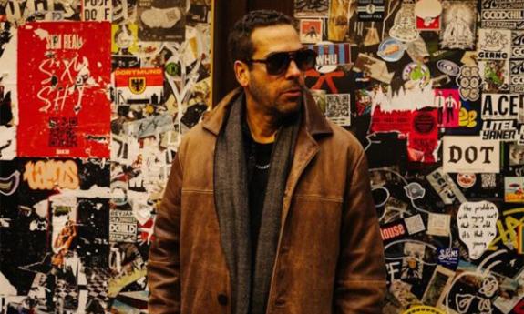Albert Castiglia wears dark sunglasses paired with a brown jacket.