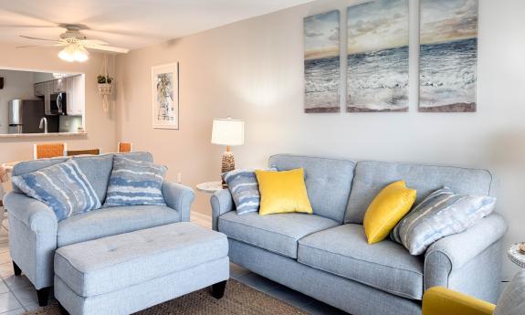The living room has blue sofa and large chair, and a yellow accent chair